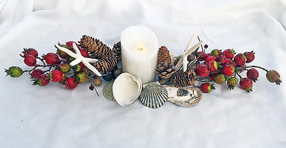 Curl the stems from the rose hip sprays around the candle, add the pine cone pics and arrange the shells around the candle so that all the stems are hidden.